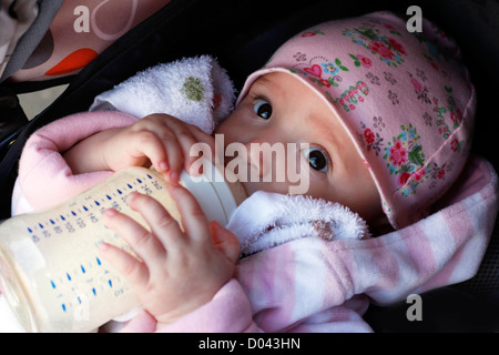 La bambina mangia la crema di farina e di latte da una bottiglia Foto Stock