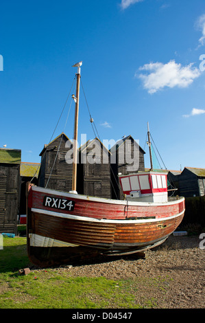 Una tradizionale storica barca da pesca in legno in mostra nella vecchia Hastings in Kent con vecchi edifici di essiccazione della rete sullo sfondo. Foto Stock