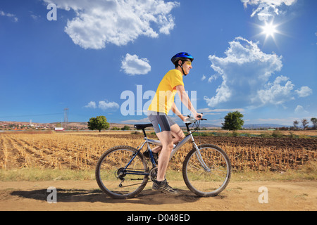 Maschio in maglietta gialla in sella ad una mountain bike in una giornata di sole, Macedonia Foto Stock