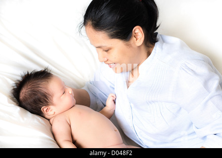 La madre e il neonato insieme su un letto bianco Foto Stock