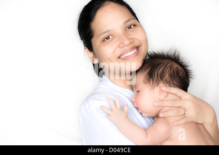 Madre detiene il neonato su un letto bianco Foto Stock