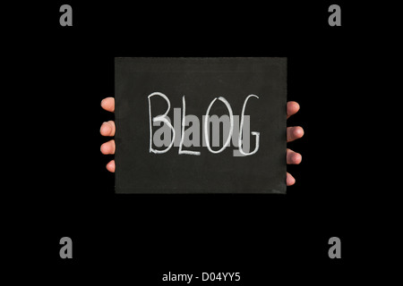 Mani tenendo una lavagna con la parola blog su di esso contro uno sfondo nero Foto Stock