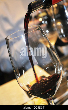 Il vino rosso è versata in un bicchiere Foto Stock