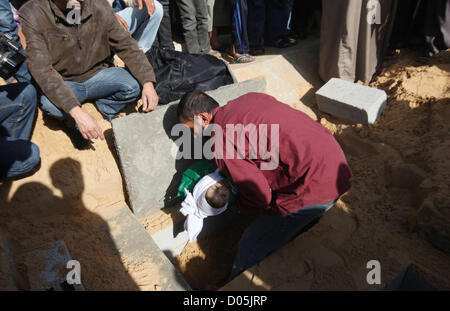 Nov. 18, 2012 - Gaza City, nella Striscia di Gaza, Territori palestinesi - un uomo palestinese porta il corpo di uno dei bambini alla tomba durante il loro funerale nel nord della Striscia di Gaza il 18 novembre 2012. Due bambini Jumana Abu Seifan, 18 mesi di età, e suo fratello Tamer, tre anni e mezzo di età, sono stati uccisi in un attacco aereo israeliano di domenica, ospedale hanno detto i funzionari. Israele ha bombardato obiettivi militante nella Striscia di Gaza per un quinto dritto nella giornata di domenica, il lancio di antenna e attacchi navali come suo militare preparato per una possibile invasione di terra, sebbene Egitto visto ''Some indicazioni'' di una tregua in avanti (credito mi Foto Stock