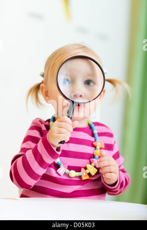 Il Toddler girl guardando attraverso la lente di ingrandimento Foto Stock