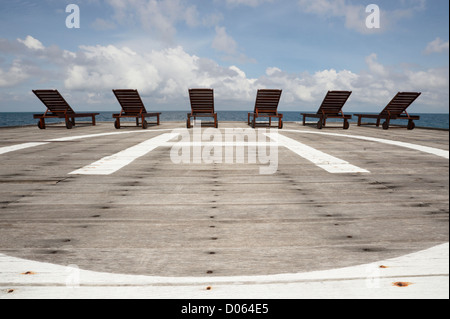 Sedie a sdraio su helipad affacciata sull'oceano Foto Stock