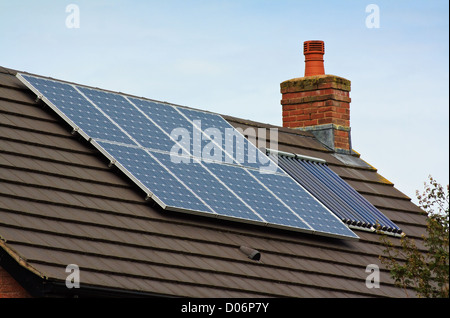 Solare fotovoltaico e riscaldamento centrale dei pannelli sul tetto di tegole di casa residenziale Foto Stock