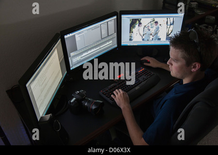 Giovani maschi adulti videografo editing di un video del matrimonio sul suo sistema di computer Foto Stock