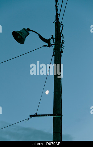 Palo del telegrafo al tramonto con la Luna in cielo. Foto Stock