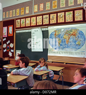 Gli scolari elementari seduti alla scrivania in un 90s classe con una mappa o il mondo Lantzville, British Columbia Canada KATHY DEWITT Foto Stock