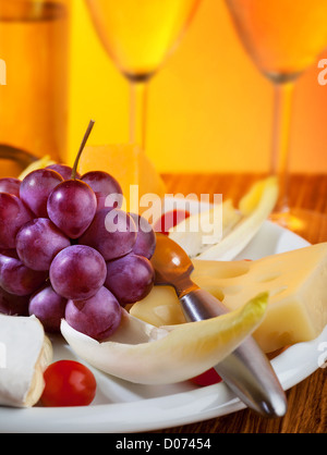 Foto di due bicchiere di champagne e uva con il formaggio sulla piastra, bevande alcoliche con gustosi stuzzichini, uva bianca vino Foto Stock