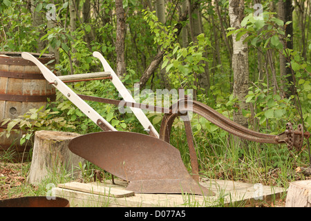 Un antico coperto di ruggine una quota aratro lasciato in un bosco di betulle in primavera a Winnipeg, Manitoba, Canada Foto Stock