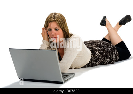 Una giovane donna sdraiata sul pavimento e lavorare sul proprio portatile Foto Stock
