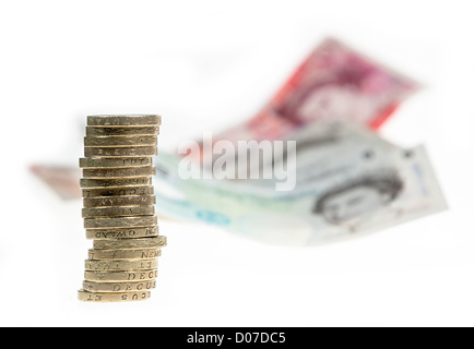 Sterlina inglese di denaro con cancelletto monete in una pila e le banconote in distanza REGNO UNITO Foto Stock
