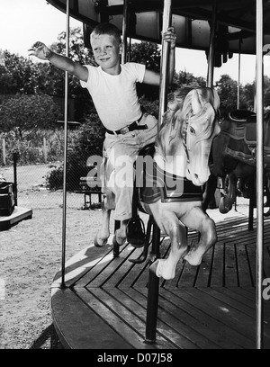 Ragazzo giovane a cavallo su merry-go-round Foto Stock