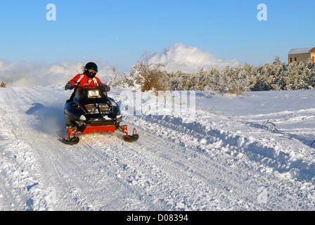 L'uomo va su una motoslitta sulla neve road Foto Stock