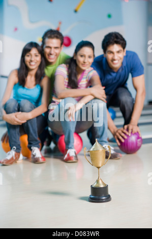 Due giovani coppie con le palle da bowling e un trofeo in una pista da bowling Foto Stock