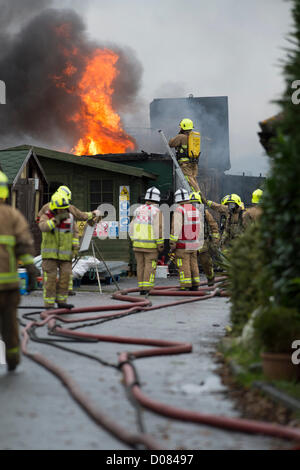 Poco Warley, Essex, Regno Unito. Circa 5am questa mattina un incendio ha cominciato ad un olio da cucina usato impianto di riciclaggio. Ingenti danni è stato causato ma non ha riportato lesioni. All'altezza di Blaze, Essex fuoco e di salvataggio aveva 12 pompe in frequenza. Era una situazione molto complicata e pericolosa incidente per il servizio antincendio. Un vigile del fuoco su una scala di attaccare il fuoco sul tetto. Foto Stock