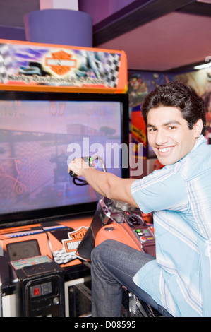 Giovane uomo la riproduzione del video gioco in una galleria video Foto Stock