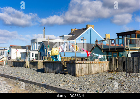 Colorato villaggio costiero case Borth Galles centrale il cui giardini torna sulla spiaggia, mare difese, linee di lavaggio, driftwood Foto Stock