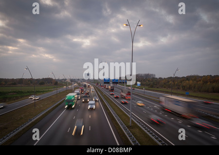 Dutch Autostrada A67 con camion e il traffico a Eindhoven nei Paesi Bassi alla sera Foto Stock