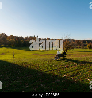 Scena autunnale a Gadebridge Park, Hemel Hempstead, Hertfordshire, Regno Unito. 2 persone su una panchina godendo il panorama. Foto Stock