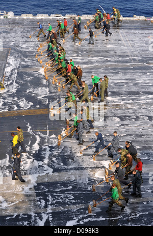 I marinai a bordo della portaerei USS George Washington (CVN 73) scrub il ponte di volo durante un ponte di volo verso il basso di lavaggio. George Foto Stock