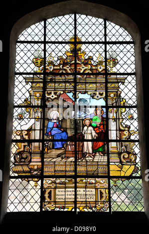 Mechelen (Malines), Belgio. Sint Katelijenkerk / chiesa. Finestra di vetro colorato. Gesù, Maria e Giuseppe nel laboratorio di falegnameria Foto Stock