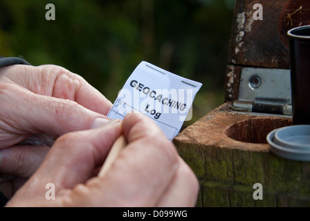 Il riempimento del registro di geocache dopo aver trovato la cache. Geocaching, Sheffield South Yorkshire, Inghilterra. Foto Stock