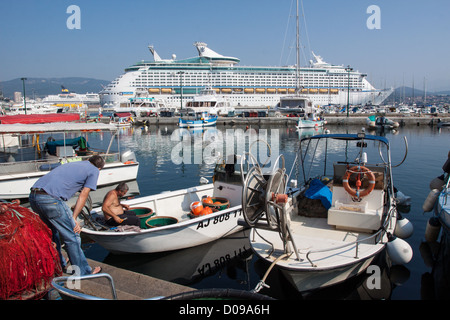 Il contrasto tra le piccole imbarcazioni da pesca immensa nave da crociera dalla Compagnia Royal Caribbean International porta a sud di Ajaccio Foto Stock