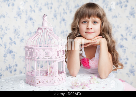 Offerta romantica sognante ragazza con i capelli ondulati vicino a aprire birdcage Foto Stock