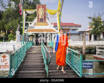 Nov. 21, 2012 - Bangkok, Tailandia - un monaco buddhisti passa sotto una foto di Bhumibol Adulyadej, del re di Thailandia, come egli assi un traghetto per andare a Bangkok sul Fiume Chao Phraya. Una rete di traghetti collega la sezione di Thonburi di Bangkok a Bangkok il corretto, attraversando il Fiume Chao Phraya. Il prezzo del biglietto è di 3 baht tailandese, circa $ 0.15 (US). Le barche sono il modo più veloce per arrivare da nord a sud di Bangkok. Migliaia di persone si reca al lavoro ogni giorno sul Fiume Chao Phraya Express barche e barche veloci che tela Khlong Saen Saeb. Le barche sono usati per trasportare merci attraverso la città di acque profonde per porte e Foto Stock