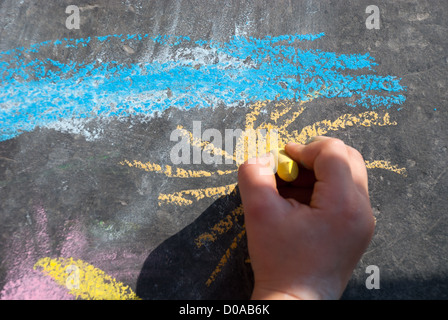 Bambino disegno a mano un cielo e un sole con gessi colorati Foto Stock