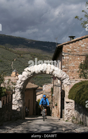 Ciclista e l'arco romano a Spello, Umbria, Italia Foto Stock