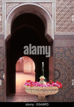 Fontana tradizionale pieno di fiori nel cortile di un palazzo Marocchino (MEDERSA) marrakech marocco AFRICA Foto Stock