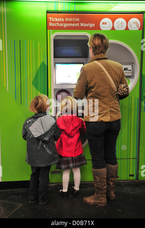 La donna e i suoi figli l'acquisto di biglietti della metro da un distributore automatico parigino della stazione della metropolitana di Parigi (75) FRANCIA Foto Stock