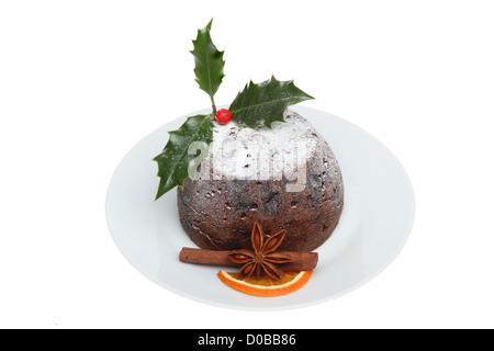 Pudding natalizio su una piastra decorate con agrifoglio e spezie isolata contro bianco Foto Stock