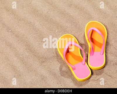 Coppia di orange flip flop sulla spiaggia Sfondo sabbia Foto Stock