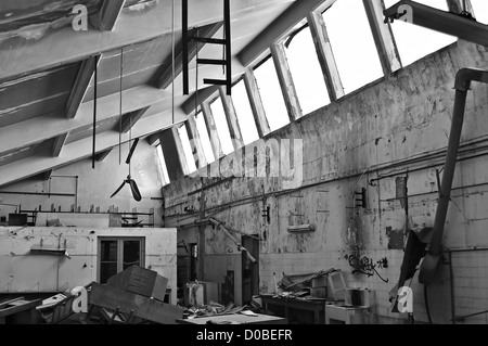 Attrezzature fracassato nel decadere interno della fabbrica abbandonata. In bianco e nero. Foto Stock