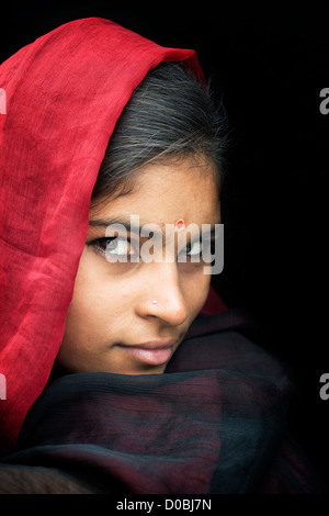 Ragazza indiana indossando un velo di colore rosso su sfondo nero. Andhra Pradesh, India Foto Stock