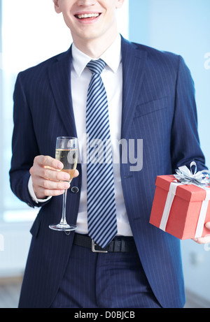 Close-up di imprenditore nel soddisfare azienda flûte di champagne e giftbox Foto Stock