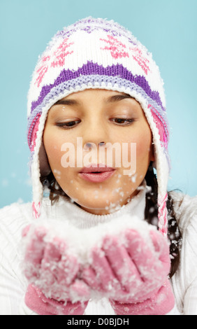 Immagine di Pretty Woman in rosa e guanti a maglia Cappello invernale lavori di soffiaggio della neve dai suoi palmi Foto Stock