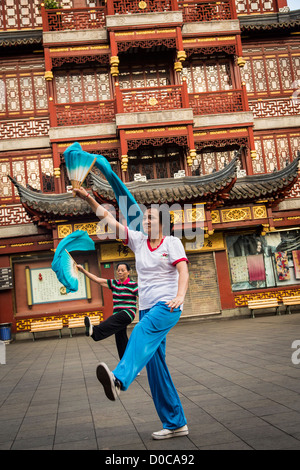 Una donna anziana esegue il cinese la danza della ventola per esercitare nella storica Yu Yuan Gardens Shanghai, Cina Foto Stock