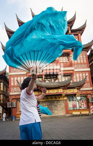 Una donna anziana esegue il cinese la danza della ventola per esercitare nella storica Yu Yuan Gardens Shanghai, Cina Foto Stock