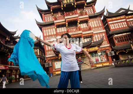 Una donna anziana esegue il cinese la danza della ventola per esercitare nella storica Yu Yuan Gardens Shanghai, Cina Foto Stock