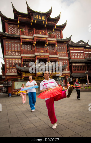 Una donna anziana esegue il cinese la danza della ventola per esercitare nella storica Yu Yuan Gardens Shanghai, Cina Foto Stock