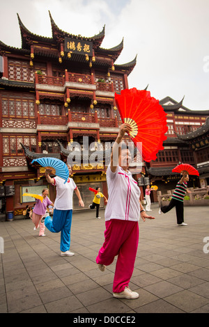 Una donna anziana esegue il cinese la danza della ventola per esercitare nella storica Yu Yuan Gardens Shanghai, Cina Foto Stock