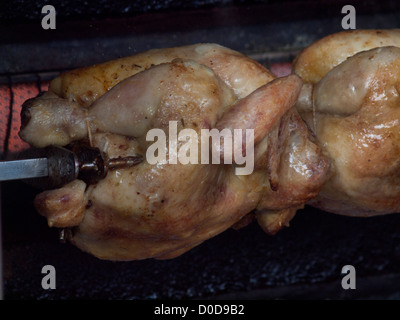 La torrefazione di polli allo spiedo in un villaggio di mercato nel nord della Francia. Foto Stock