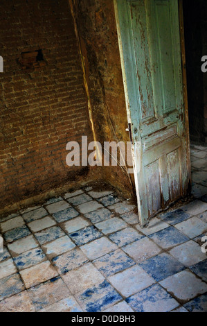 Cariati sala interna porta vecchia pavimento piastrellato e le radici che crescono su sbriciolare un muro di mattoni. Foto Stock