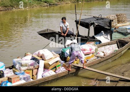 Mercato Cho Dong Ba Negozio Barche da carico in legno Fiume del Profumo Hue Vietnam | HUE, Vietnam — Barche da carico in legno caricate di stuoie tessute e merci imballate si ormeggiano lungo il Fiume del Profumo per scaricare al mercato di Cho Dong Ba. Re Thanh Thai trasferì il centro commerciale in questa posizione fluviale nel 1899 per sfruttare l'estesa rete commerciale fluviale della regione. La via d'acqua rimane un'arteria vitale per il trasporto di merci alla rinfusa dalla provincia rurale di Thua Thien-Hue direttamente nel centro città. Foto Stock